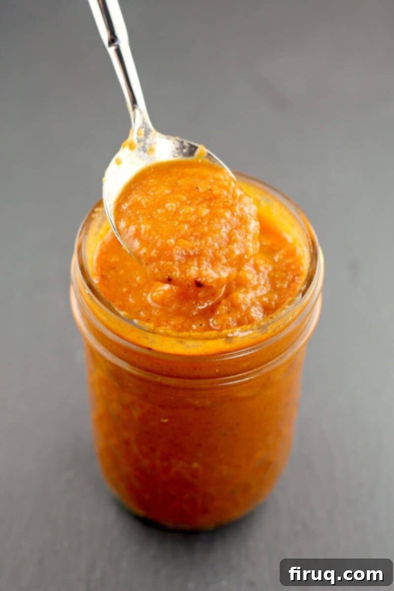 Sunrise Ranchero Kick 2 mason jar filled with huevos ranchero sauce with spoon lifting some up