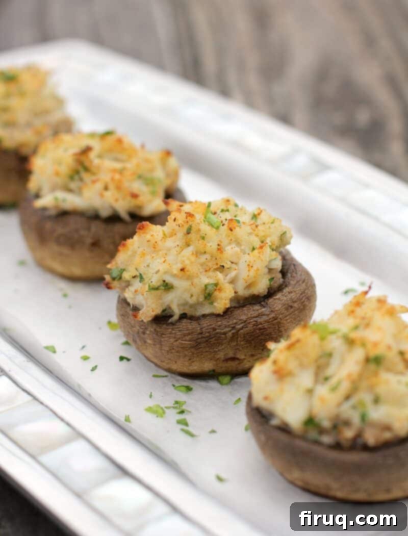 Crab-Filled Mushroom Caps 10 four stuffed mushrooms with crab in a row on serving plate