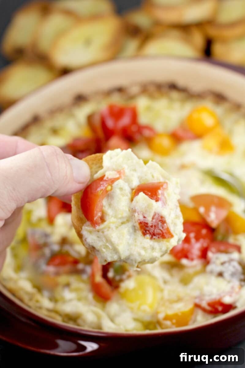 Warm Green Chili Artichoke Dip 3 hand holding a piece of toasted bread with green chili artichoke dip