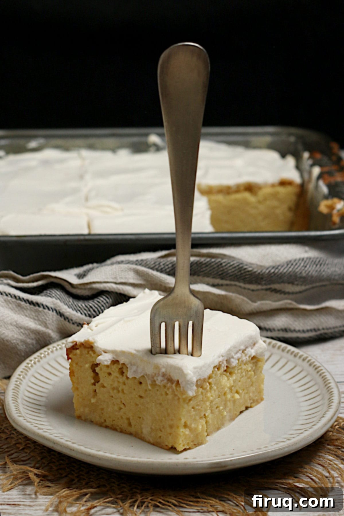 Gluten-Free Corn Tres Leches Cake Slice with Fork A slice of gluten-free Corn Tres Leches Cake with a fork stuck into it on a small white plate.