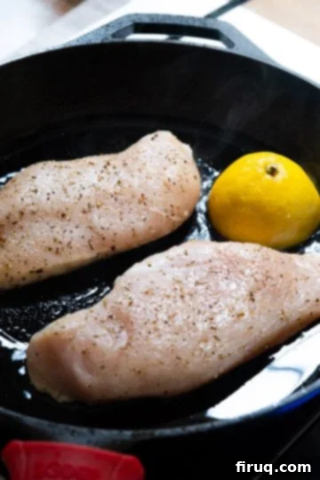 Flawless Cast Iron Chicken Breast 5 Raw chicken breast with lemon half added to a hot cast iron skillet