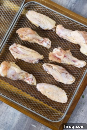 Crispy Air Fryer Garlic Parmesan Wings 5 Raw seasoned chicken wings being carefully placed in a single layer into an air fryer basket
