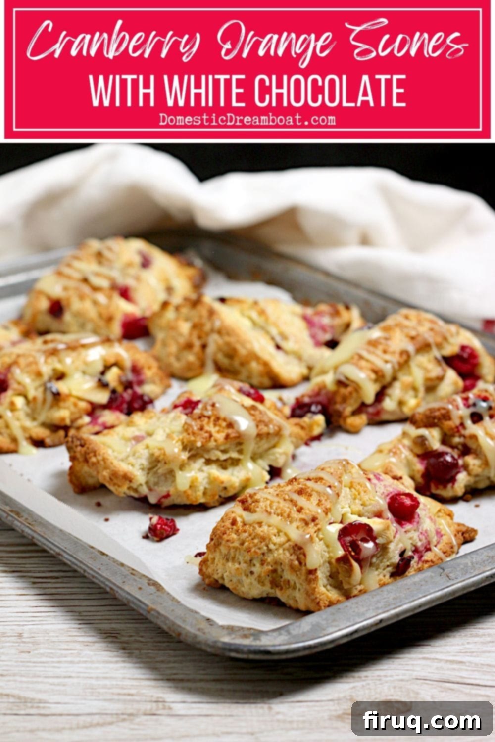 Cranberry Orange Scones with White Chocolate Two Cranberry Orange Scones with White Chocolate on a dark surface, one whole and one broken in half to show the flaky interior.