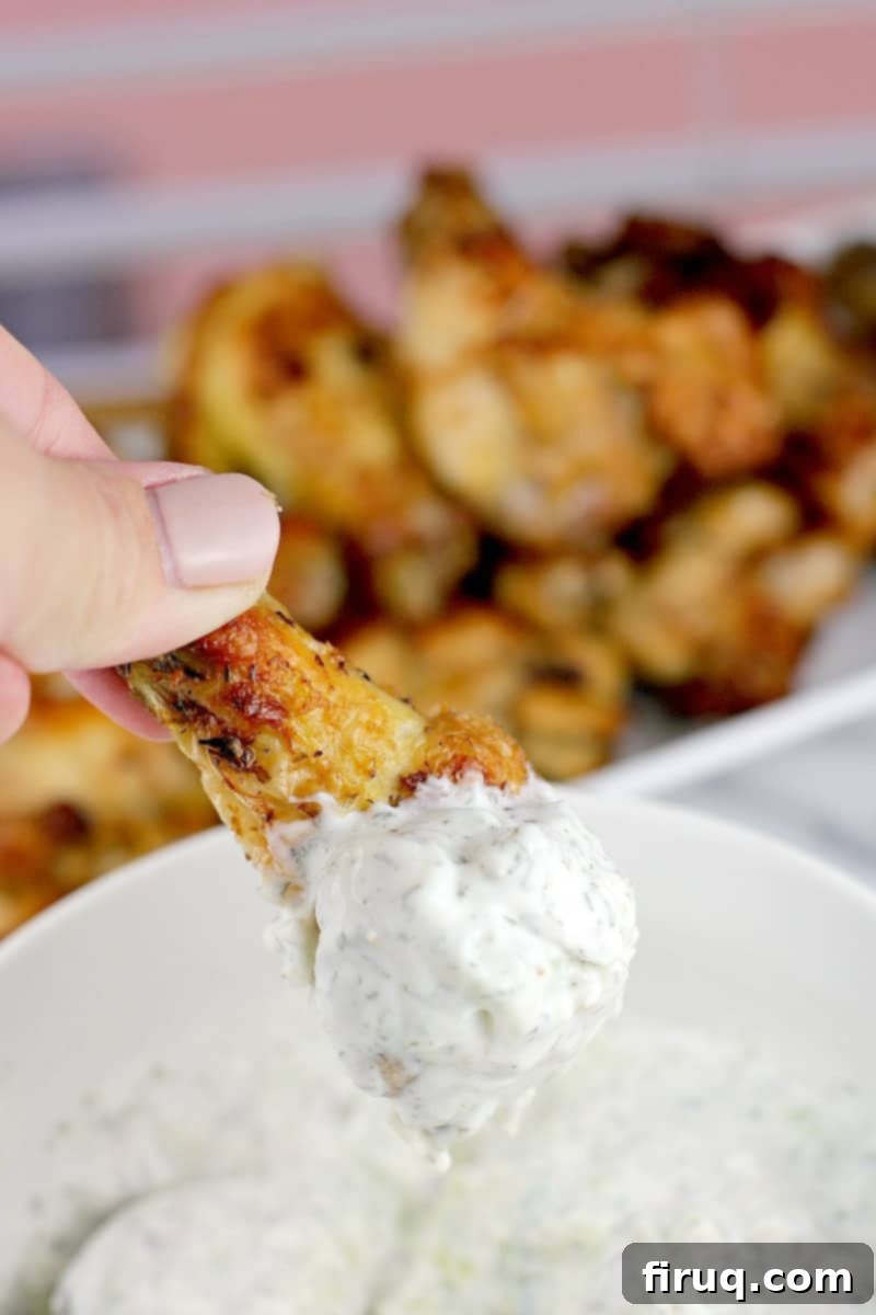 Crispy Greek Air Fryer Wings 8 hand holding a crispy Greek-Style Air Fryer Chicken Wing dipped in creamy tzatziki sauce