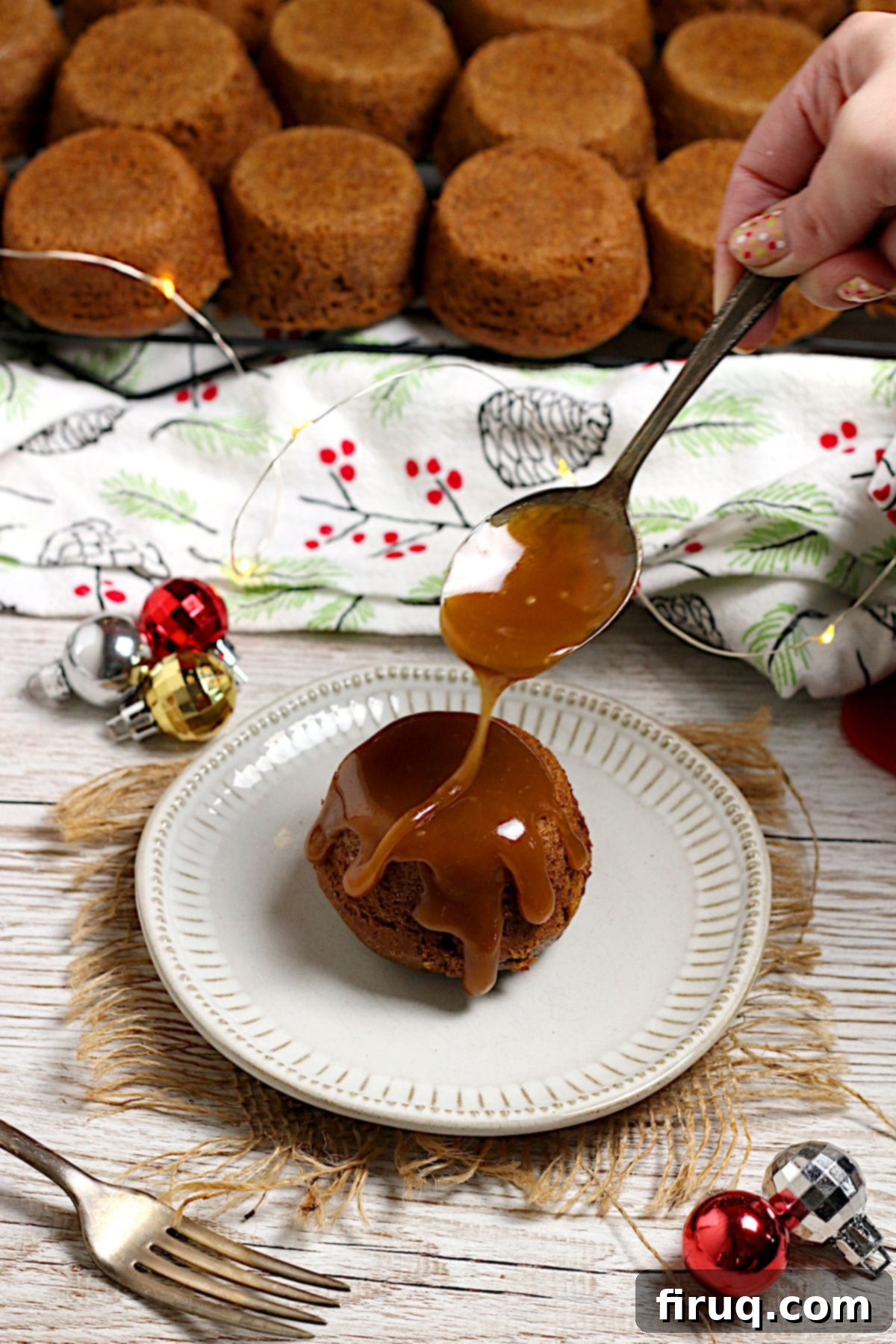 Sticky Toffee Pudding with Sauce Spooning toffee sauce onto an individual Sticky Toffee Pudding on a small white plate.