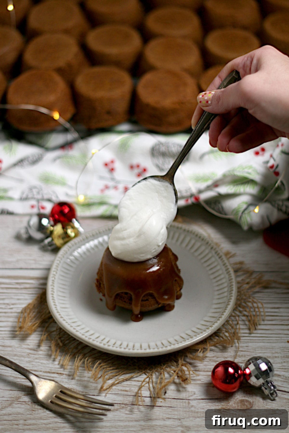 Sticky Toffee Pudding with Whipped Cream Adding a dollop of whipped cream to an individual sticky toffee pudding on a small white plate.