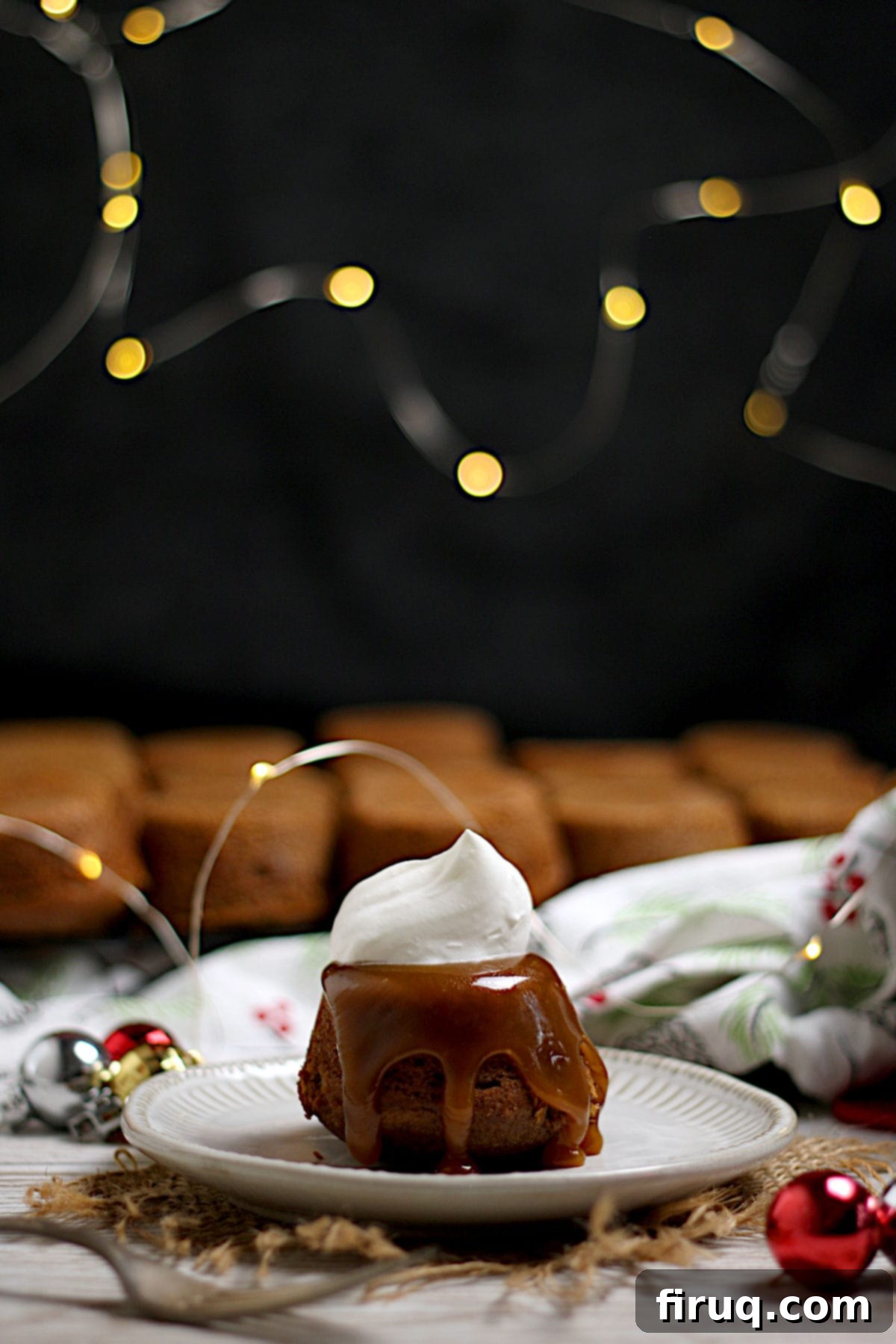 Sticky Toffee Pudding Ready to Serve An individual sticky toffee pudding with a dollop of whipped cream on a small white plate.