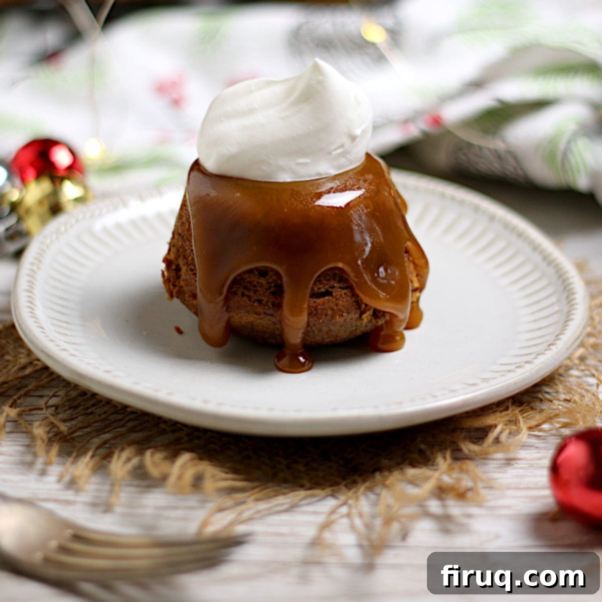 Caramel Date Delight 2 An individual sticky toffee pudding with a dollop of whipped cream on a small white plate.
