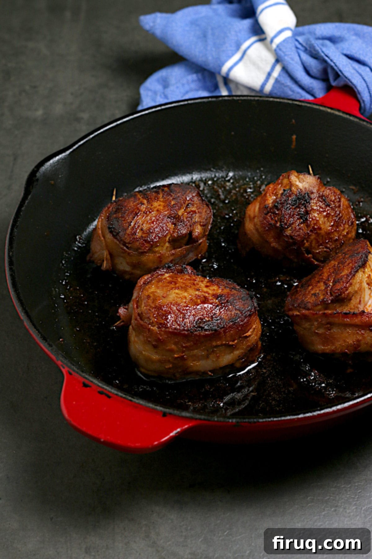 Sizzling Bacon Wrapped Pork Medallions in Skillet Smoky Bacon Wrapped Pork Medallions sizzling in a cast iron skillet, golden brown and perfectly cooked.