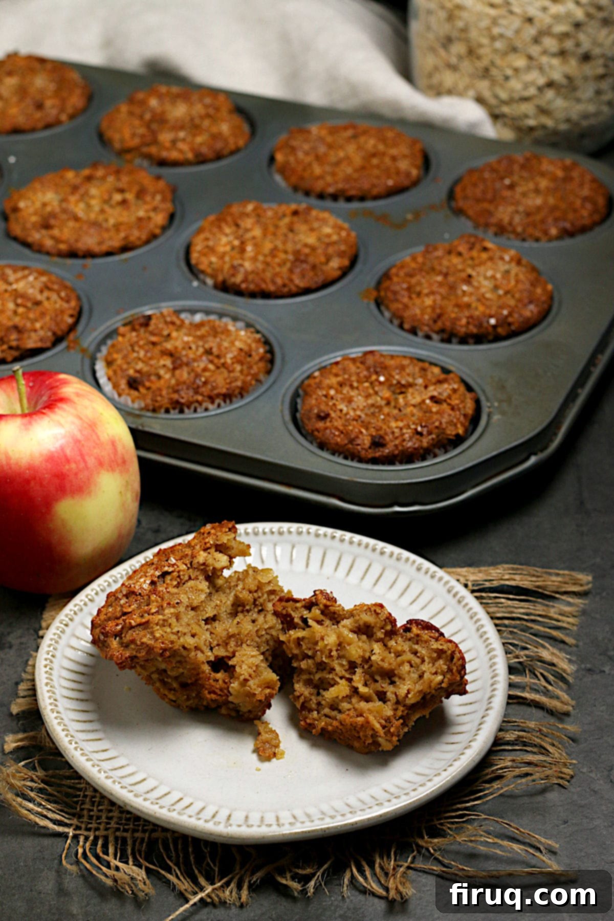 Apple Cinnamon Oatmeal Muffin Interior Texture An Apple Cinnamon Oatmeal Muffin broken in half, revealing its moist and textured interior with visible apple pieces and flecks of cinnamon. It highlights the wholesome ingredients.
