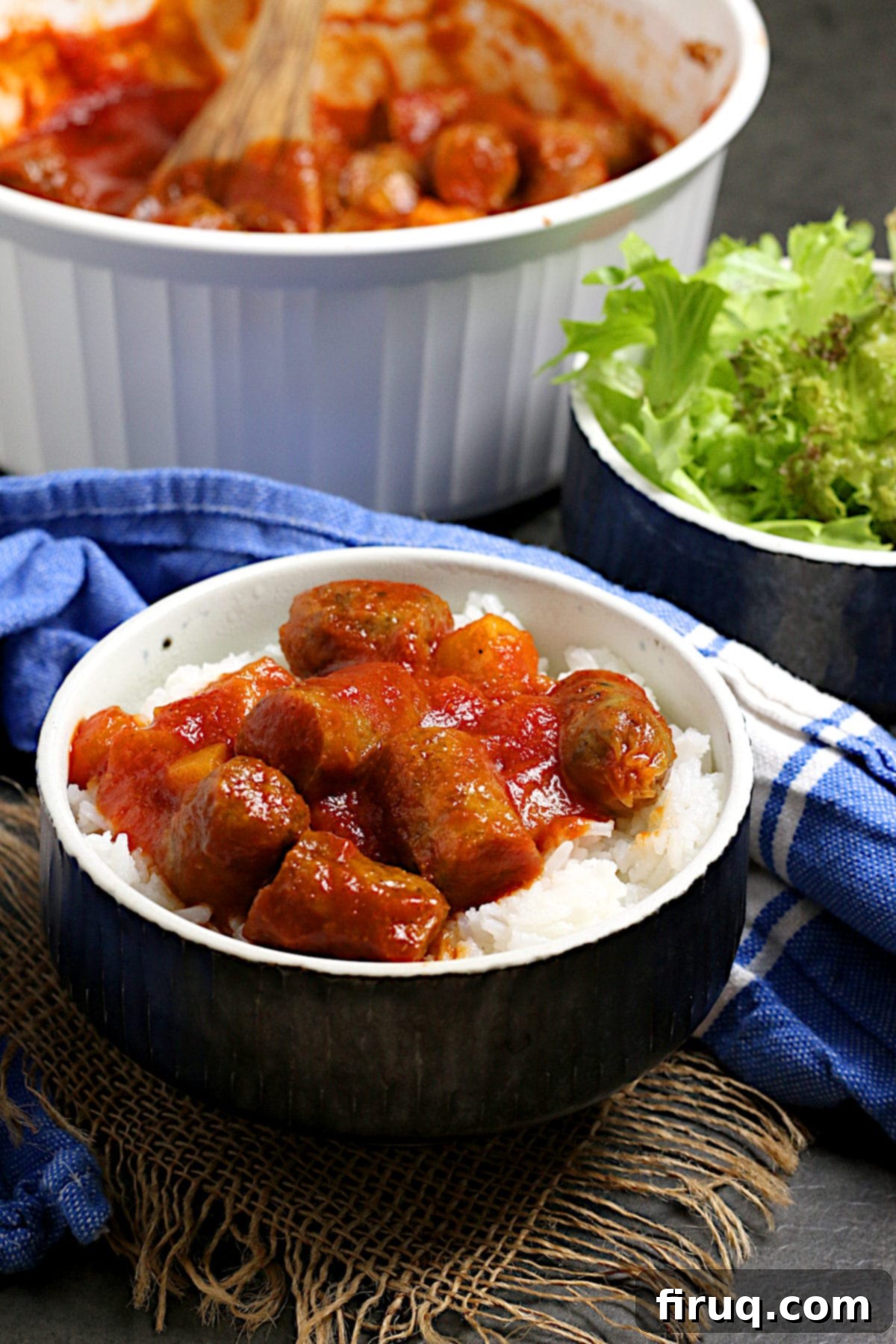 Close-up of Peachy Sweet and Sour Sausages with Rice Peachy Sweet and Sour Sausages over white rice in a black bowl.