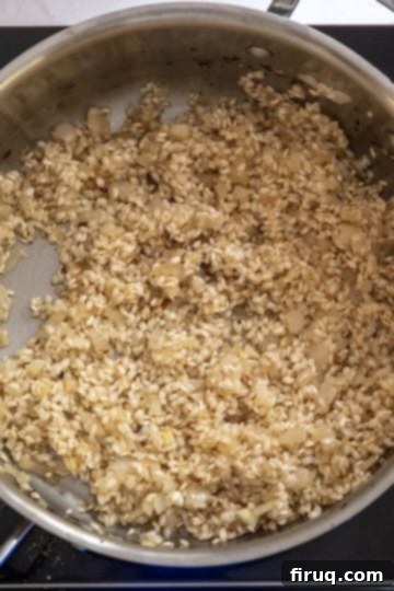 Decadent Mushroom Truffle Risotto 7 Arborio rice toasting in the pan, showing the opaque white 'pill' in the center of the grains.