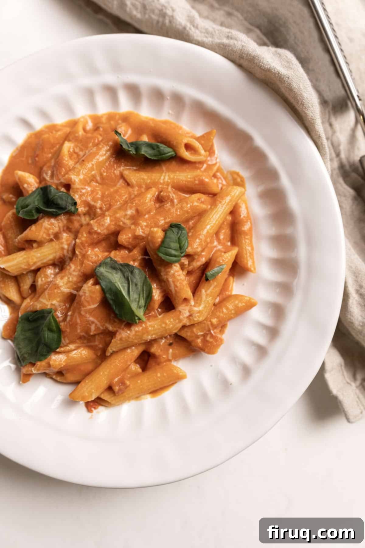 Fiery Vodka Sauce 2 A vibrant plate of penne pasta coated in a creamy, reddish-orange spicy vodka sauce, garnished with fresh herbs and a sprinkle of cheese.