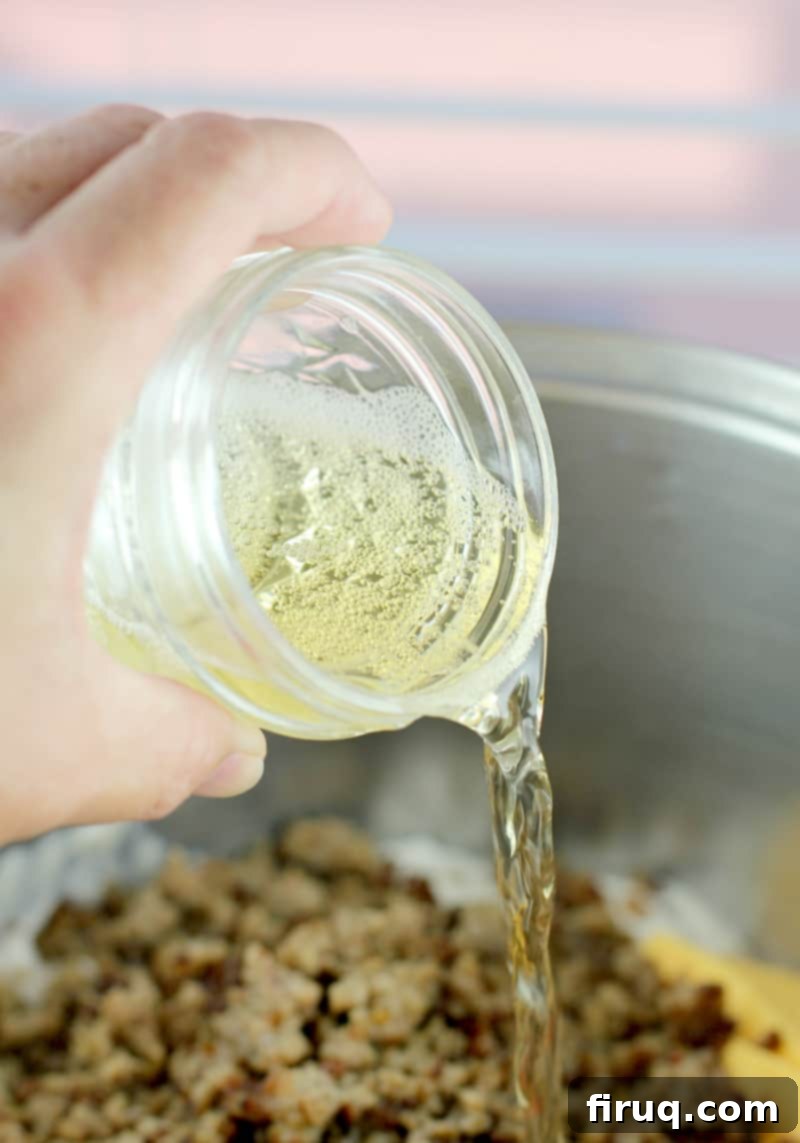 Irresistible Velveeta Rotel Sausage Dip 6 Small mason jar wiht beer being poured into the pot with the rest of the ingredients