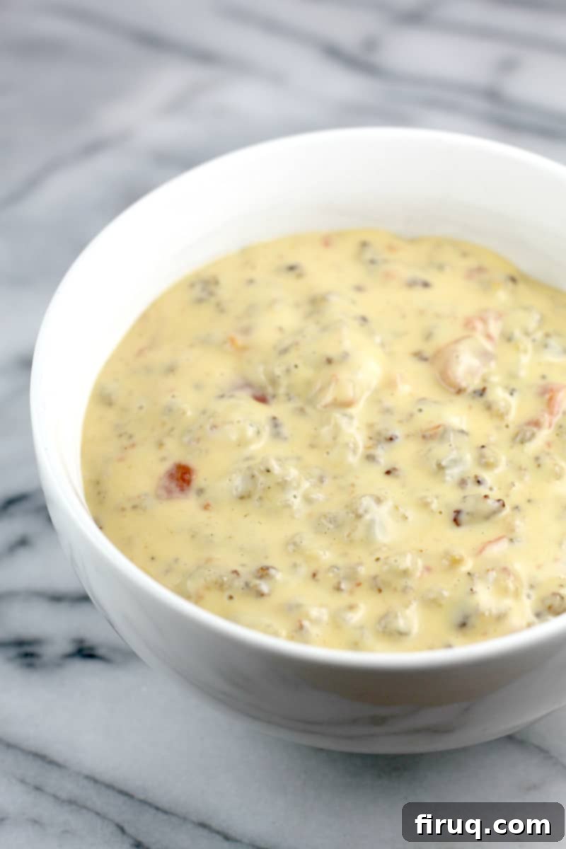 Irresistible Velveeta Rotel Sausage Dip 9 Side view of white bowl on marble surface, full of finished queso