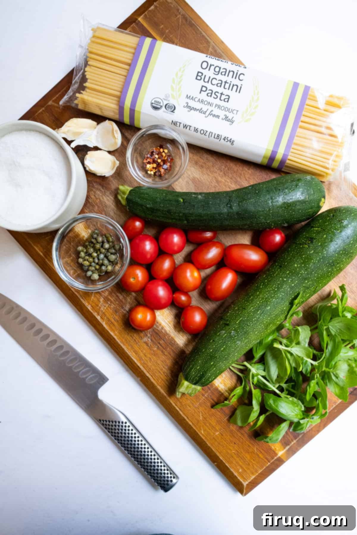 Sun-Kissed Zucchini Pasta 3 Carefully laid out ingredients for Italian Summer Zucchini Pasta, including fresh bucatini, vibrant cherry tomatoes, crisp zucchini, aromatic garlic, and fresh basil.