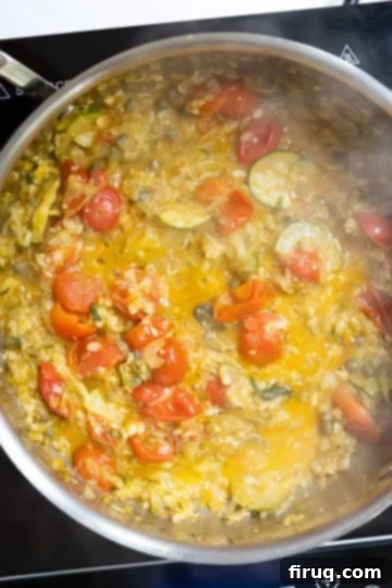 Sun-Kissed Zucchini Pasta 8 The creamy zucchini and cherry tomato sauce transforming into a deeper reddish hue and thickening after the addition of pasta water, indicating perfect consistency.
