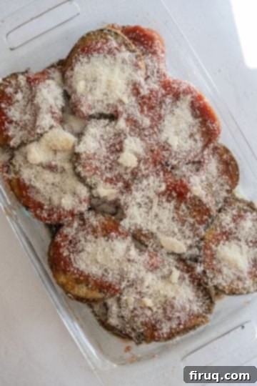 The Ultimate Homemade Eggplant Parmigiana 9 Adding a layer of Parmesan cheese over the sauce and eggplant.