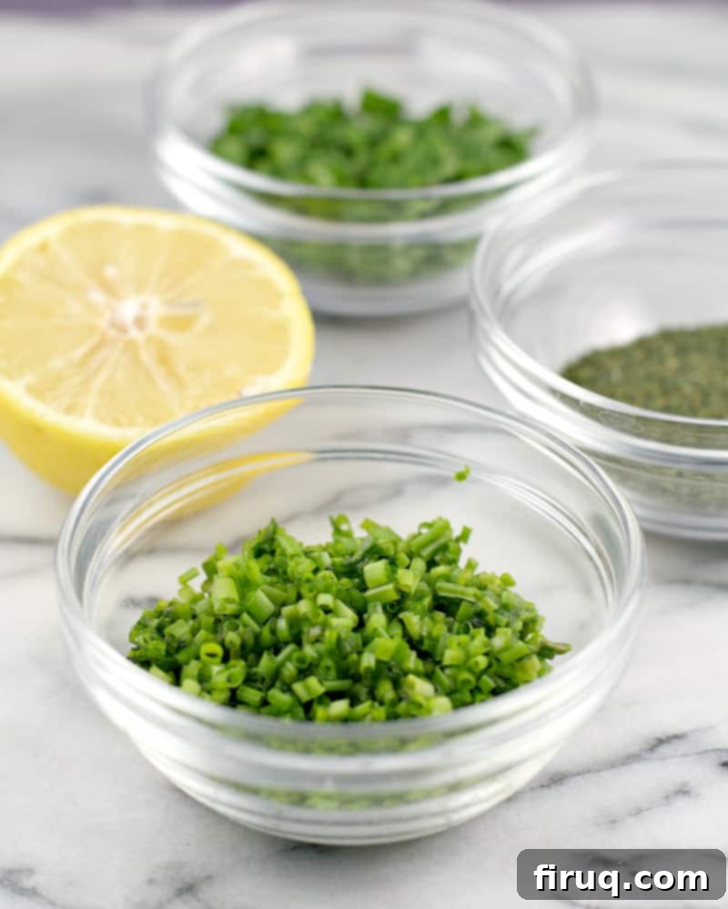 Creamy Cornucopia Salami Rolls 6 three small glass dishes showing the herbs parsley, chive, and dill, and a lemon half. marble background
