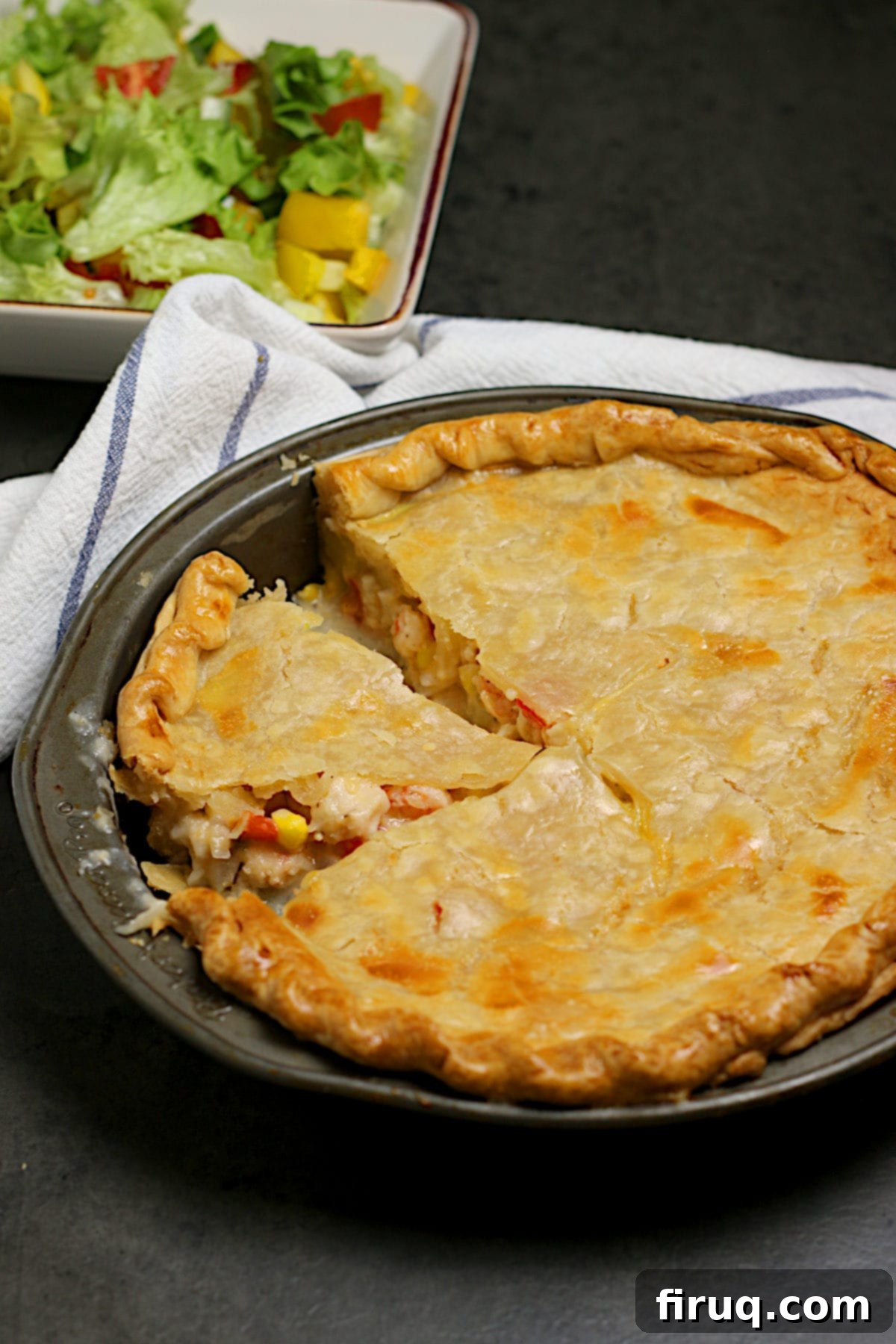 Seafood Pie with a Slice Cut A baked seafood pie in a pie pan with a slice removed, showing the creamy filling.
