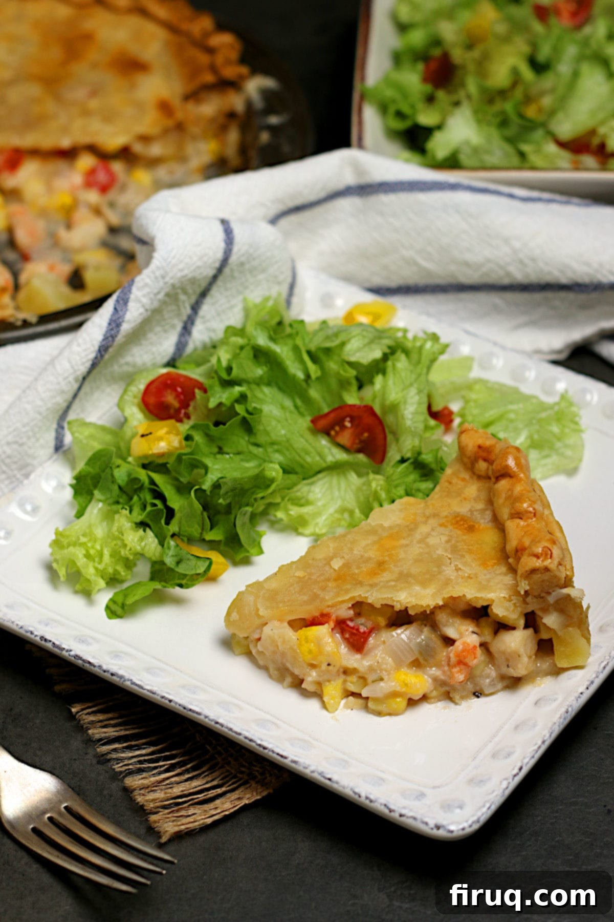Seafood Pie Slice with Salad A generous slice of seafood pie and a crisp green side salad on a elegant white square plate.