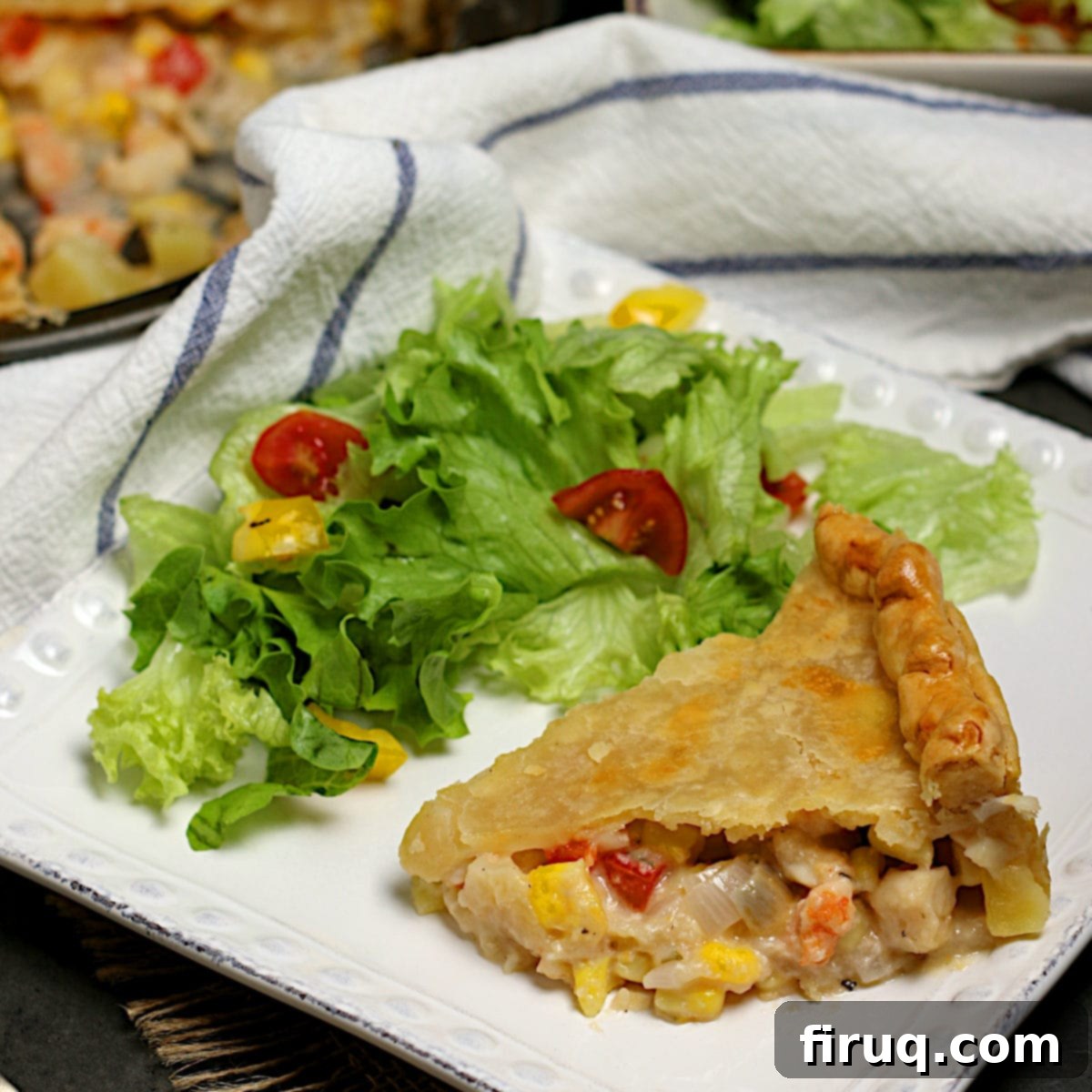 Seafood Pie Slice A slice of seafood pie and a side salad on a white square plate.
