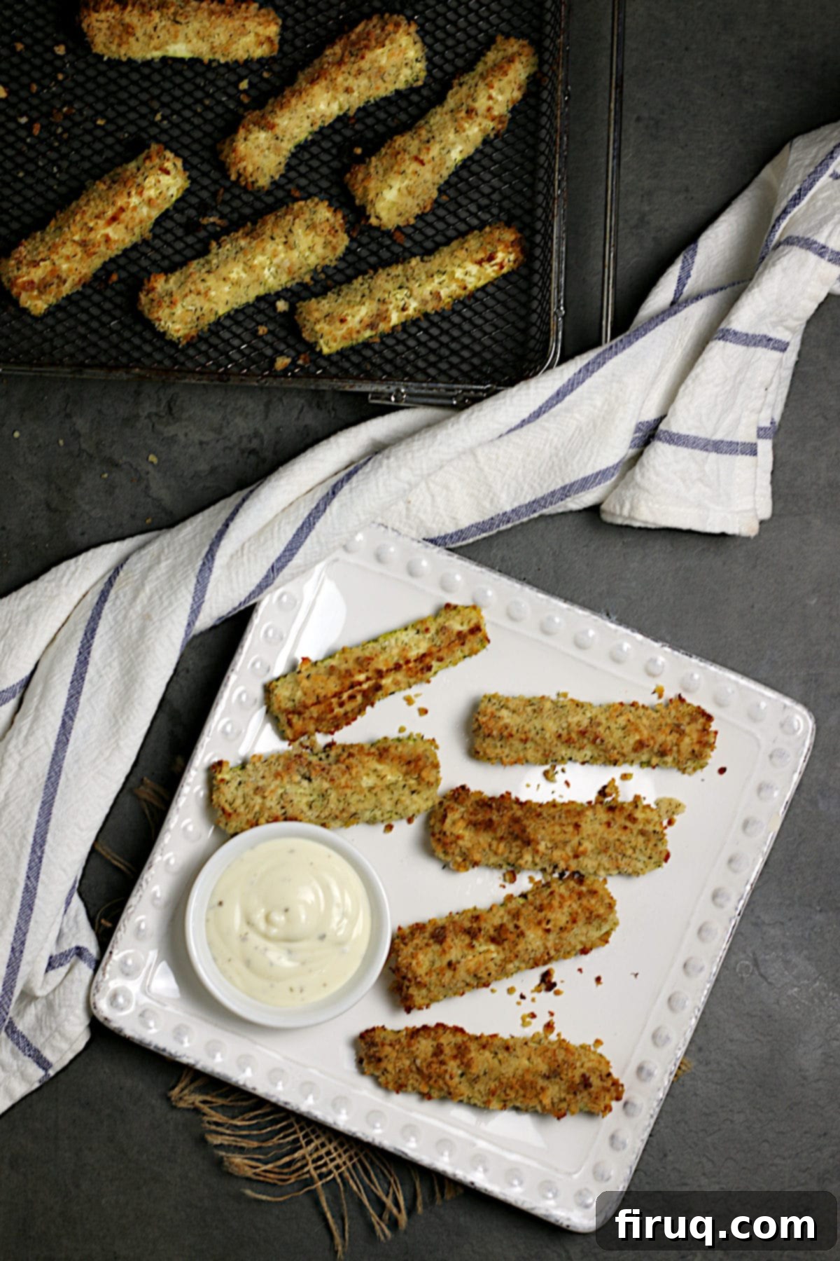 Serving Air-Fried Zucchini Sticks Overhead photo of golden-brown air-fried zucchini sticks served on a clean white square plate, showcasing their crispy texture.