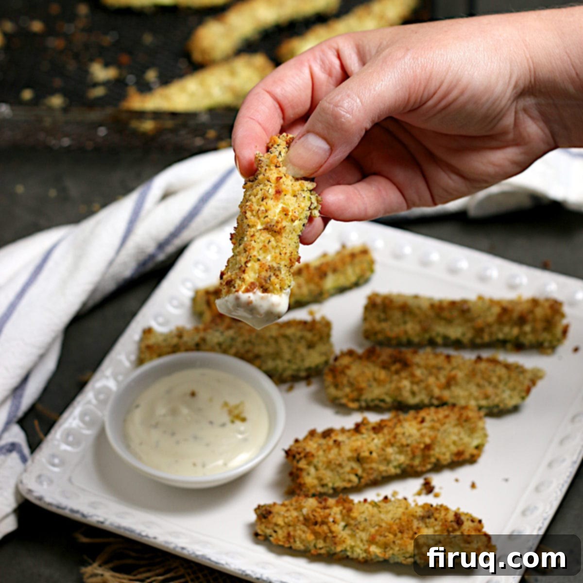 Air-Fried Zucchini Sticks with Ranch Dip A hand holding an Air-Fried Zucchini Stick that has been dipped in ranch.