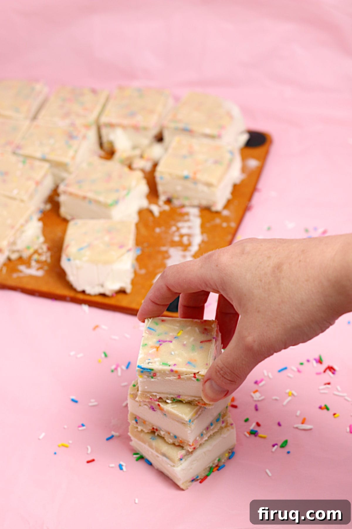 Grabbing a Funfetti Cookie Dough Ice Cream Sandwich A hand reaching for a small square funfetti cookie dough ice cream sandwich from a stack.