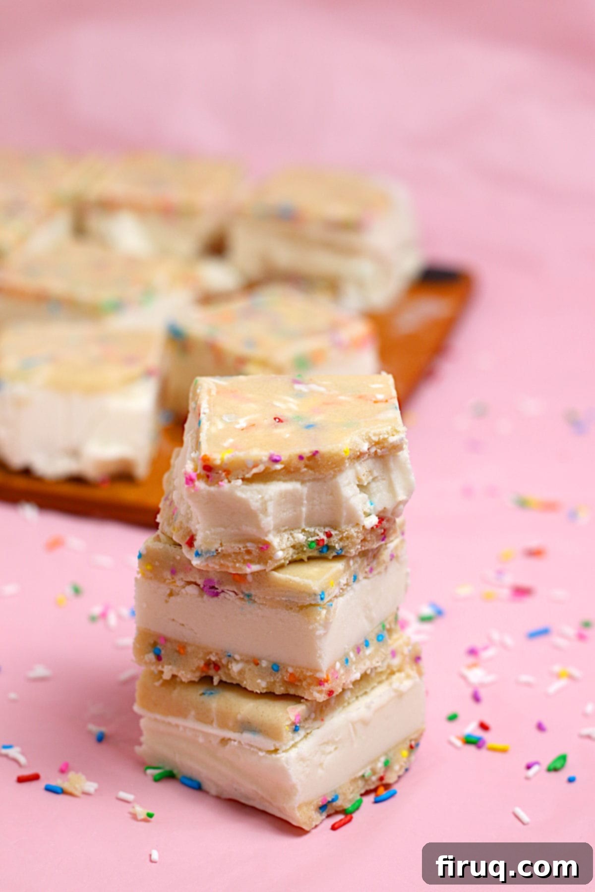 Bitten Funfetti Cookie Dough Ice Cream Sandwich Small square funfetti cookie dough ice cream sandwiches in a stack, with one having a bite taken out.