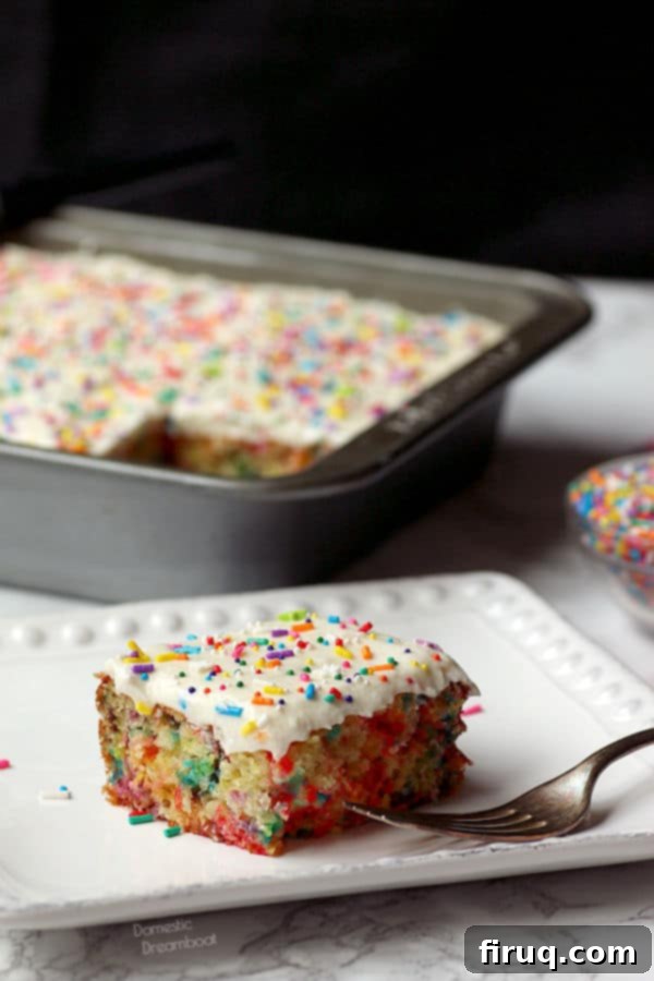 Easy Sprinkle Cake Closeup photo of a slice of sprinkle cake on a white plate, showing the festive interior.