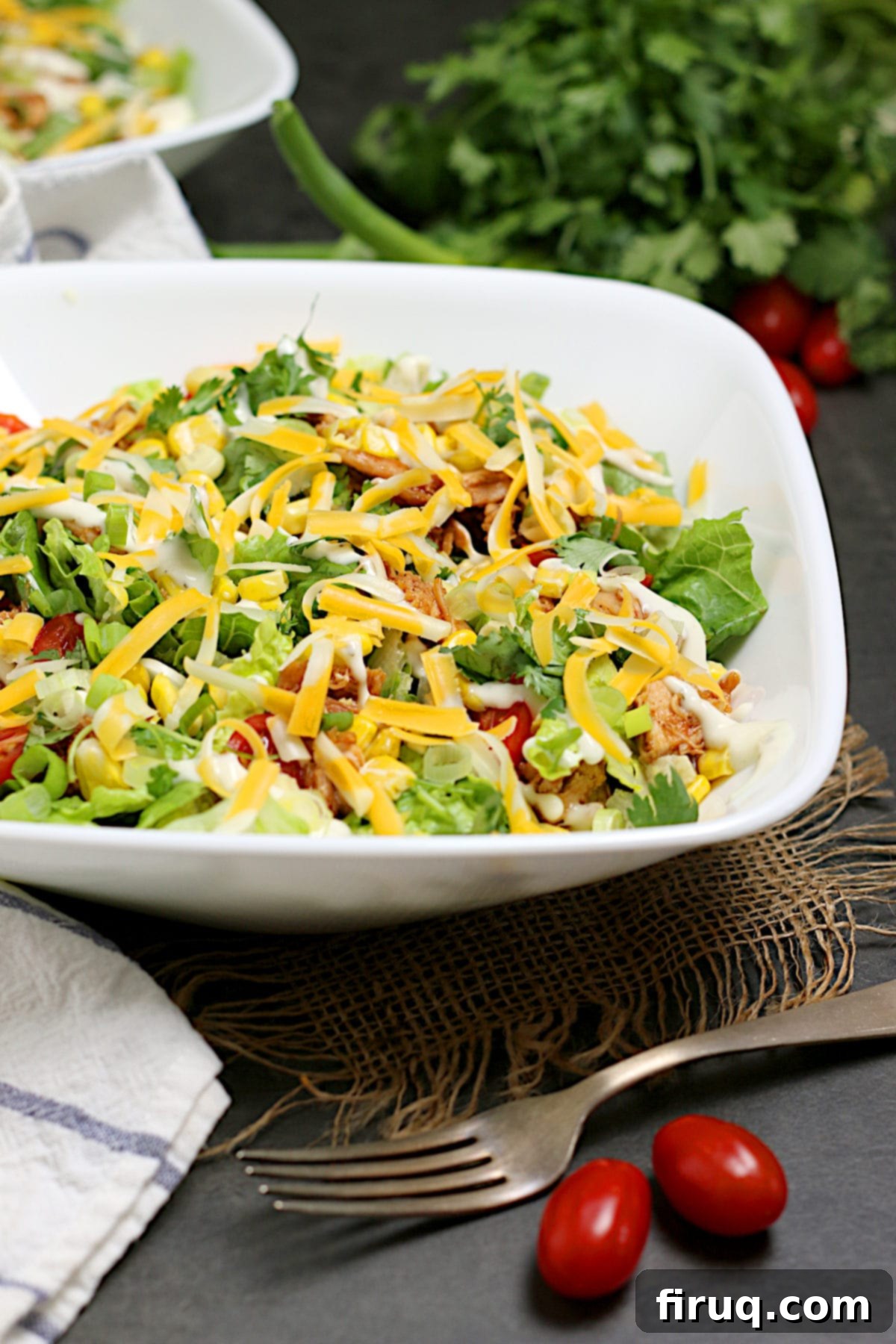 Delicious BBQ Chicken Ranch Salad Barbecue Chicken Ranch Salad in a white bowl, garnished with cilantro and green onions.