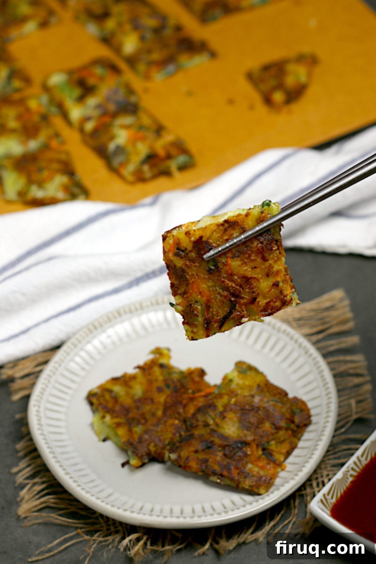 Korean Vegetable Pancake (Yachaejeon) A pair of chopsticks holding a square piece of Korean vegetable pancake.