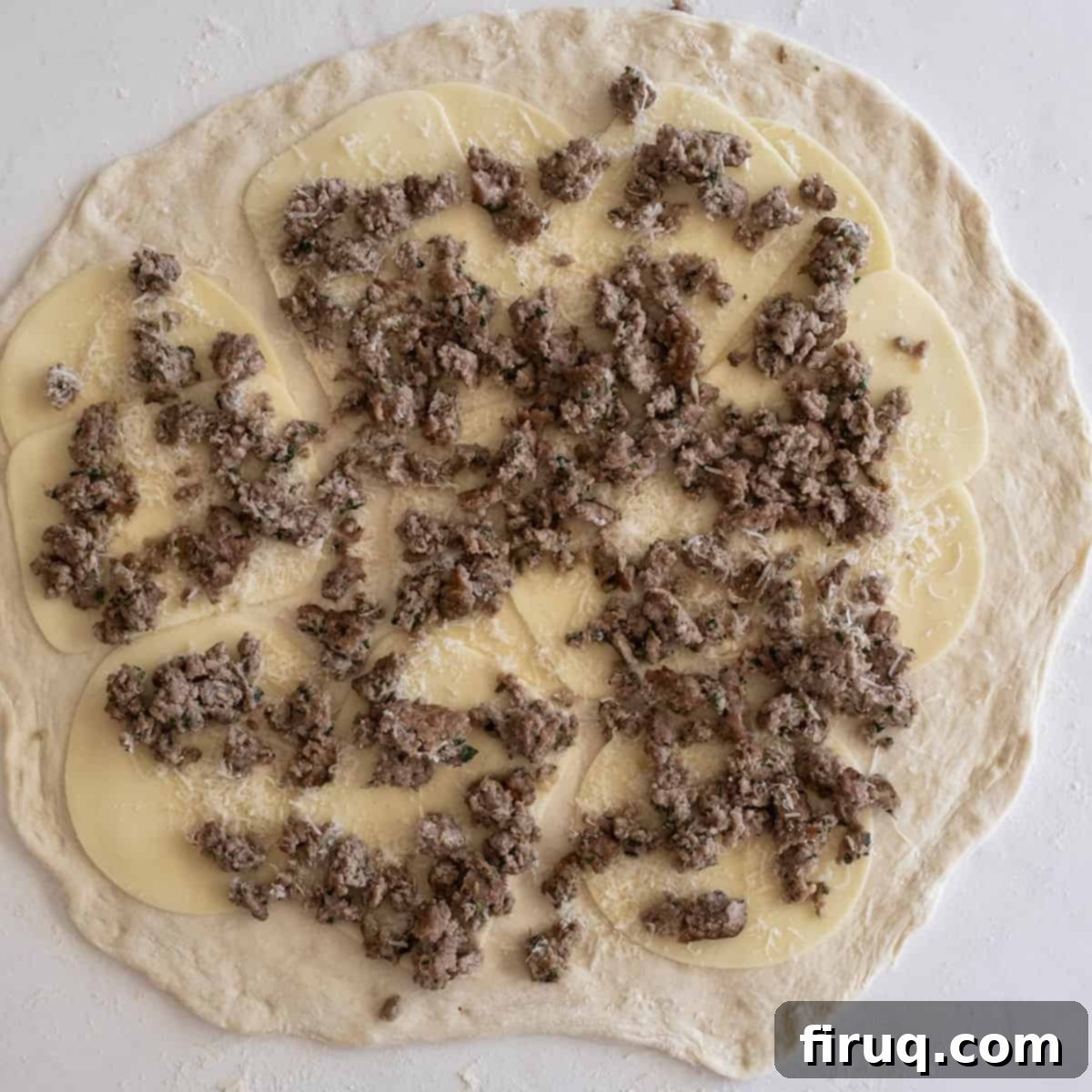 Savory Italian Sausage Bread 6 Pizza dough completely covered with ground sausage, ready to be rolled.