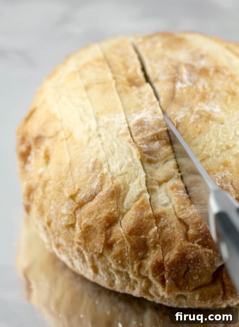 Loaded Cheesy Garlic Bread 4 A bread knife carefully cutting into the top of a crusty bread loaf, creating the signature 'cracks' for stuffing.