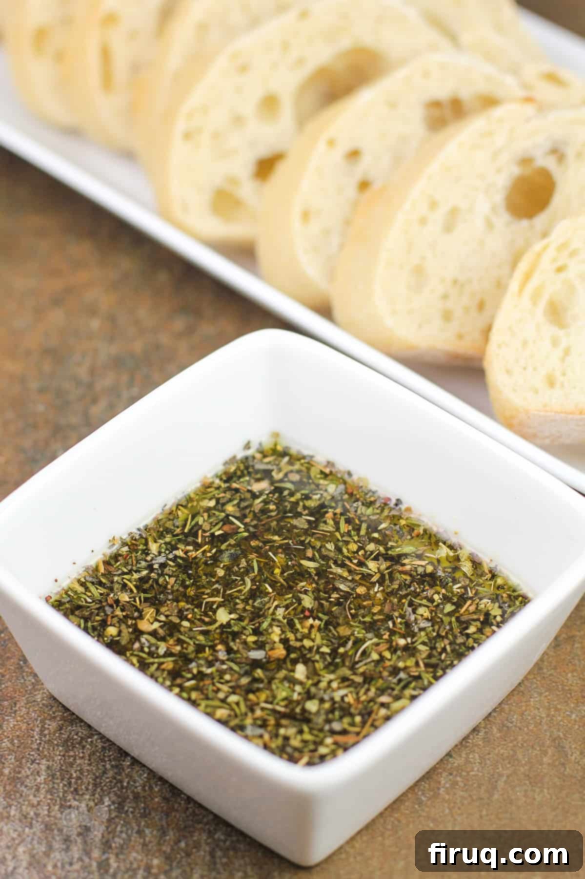 Restaurant Secret Olive Oil Bread Dip 2 prepared recipe in small white bowl; sliced bread in background