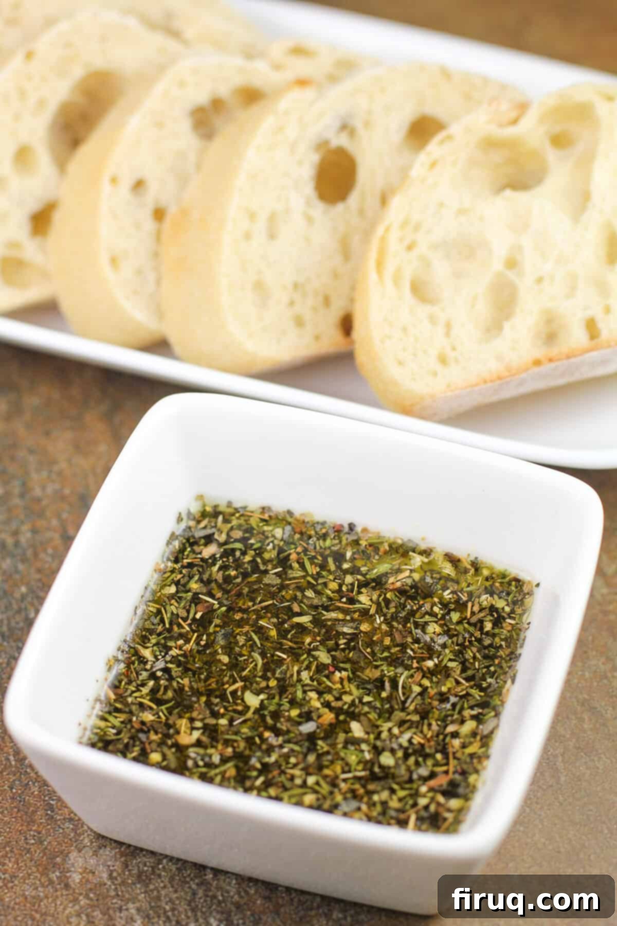 Restaurant Secret Olive Oil Bread Dip 6 prepared recipe in small white bowl; sliced bread in background