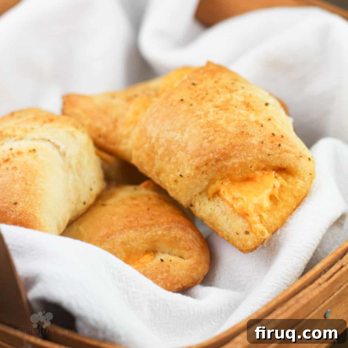 Melted Cheddar Crescent Rolls 2 Cheddar Cheese Stuffed Crescent Rolls in a rustic basket with a white napkin, perfectly baked and golden.