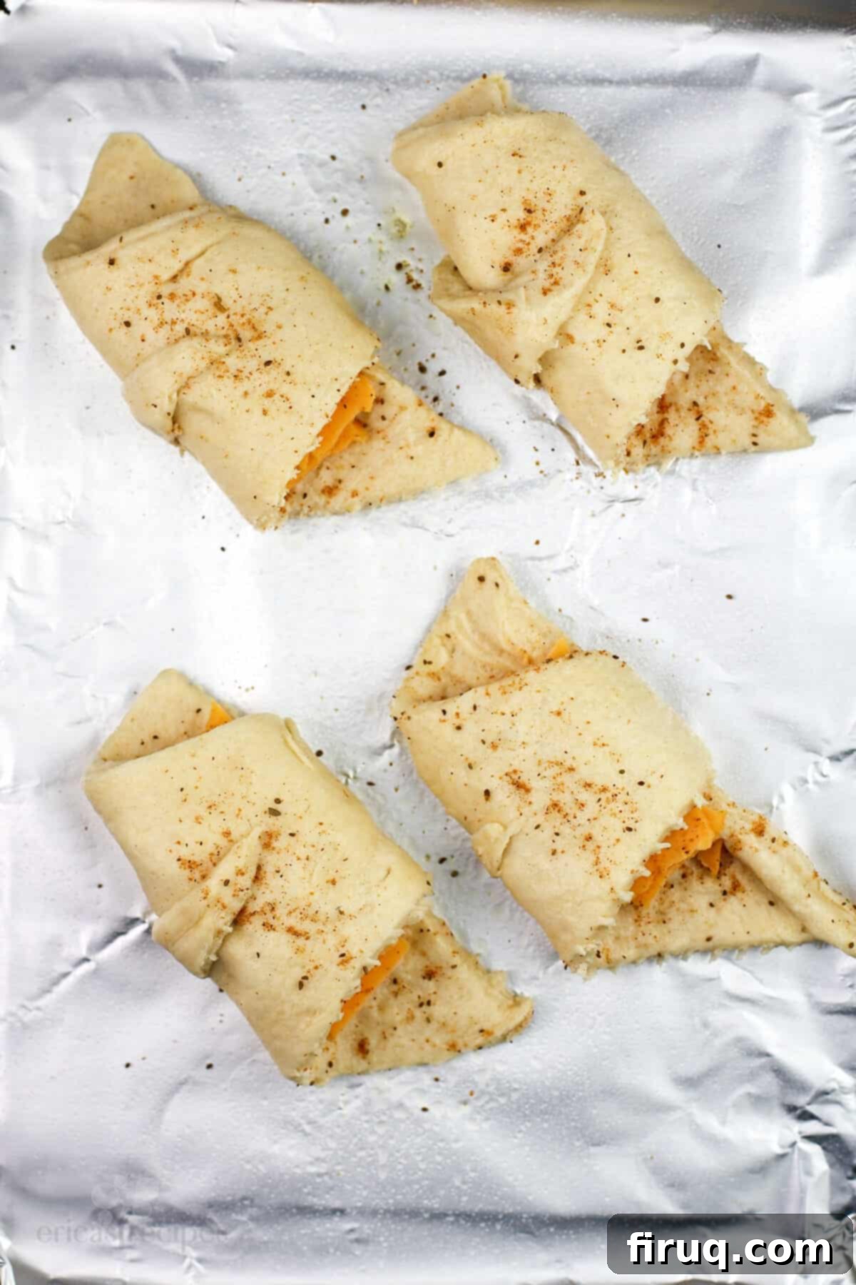 Melted Cheddar Crescent Rolls 5 Unbaked crescent rolls filled with cheddar and Old Bay, arranged on a baking sheet.
