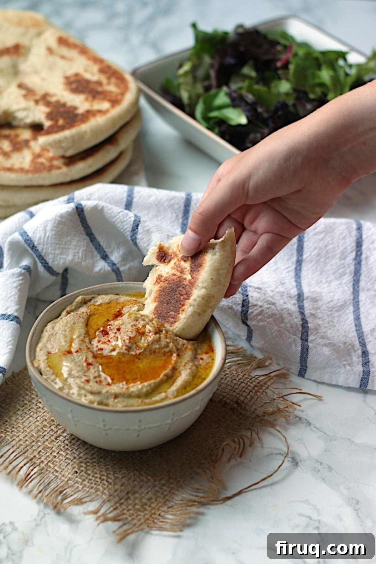 Enjoying Baba Ghanouj with Flatbread A hand dipping a piece of flatbread into a bowl of baba ghanouj, showcasing its creamy texture.