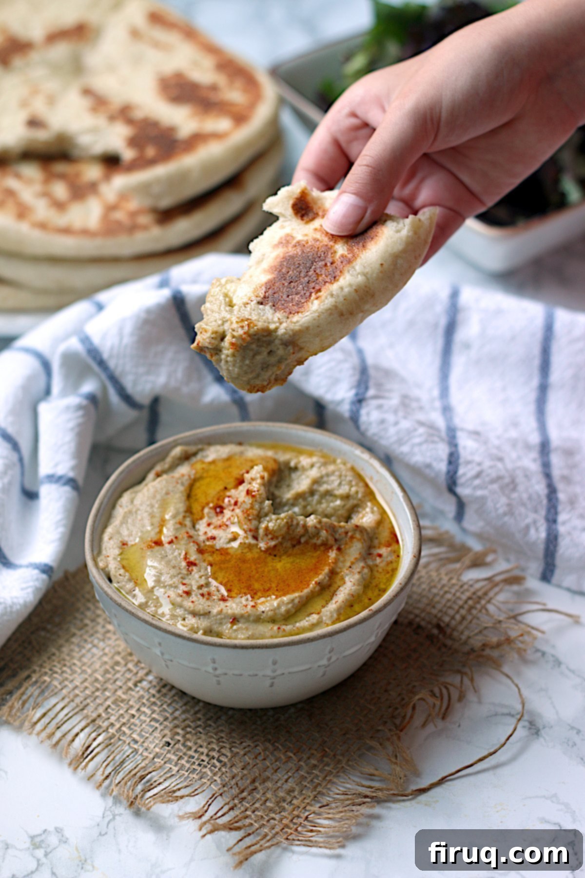 Delicious Baba Ghanouj Bite A hand holding a piece of flatbread covered in baba ghanouj, ready to eat.
