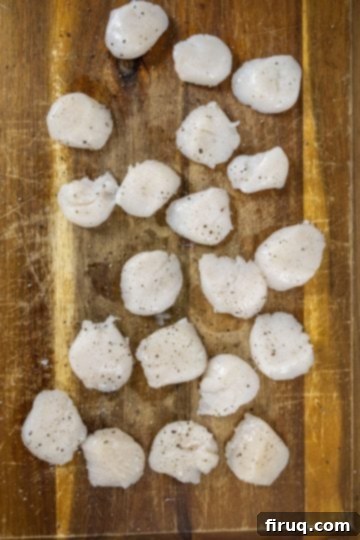 Sizzling Garlic Sage Scallops 4 seasoning scallops with salt and pepper on a cutting board