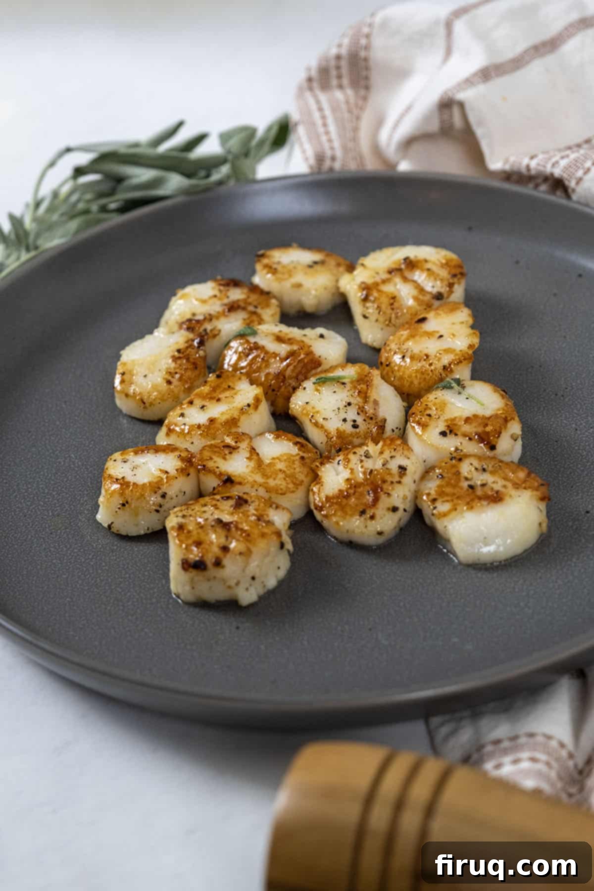 Sizzling Garlic Sage Scallops 9 garlic sage seared scallops on a white plate with lemon wedges and fresh parsley