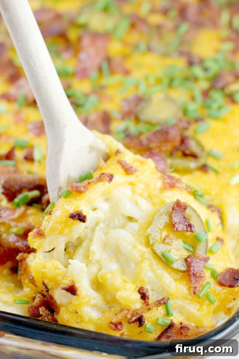 Kickin' Hash Brown Popper Casserole 6 Wooden spoon lifting a generous portion of creamy hash brown casserole with melted cheese, bacon, and jalapenos, showing its texture.