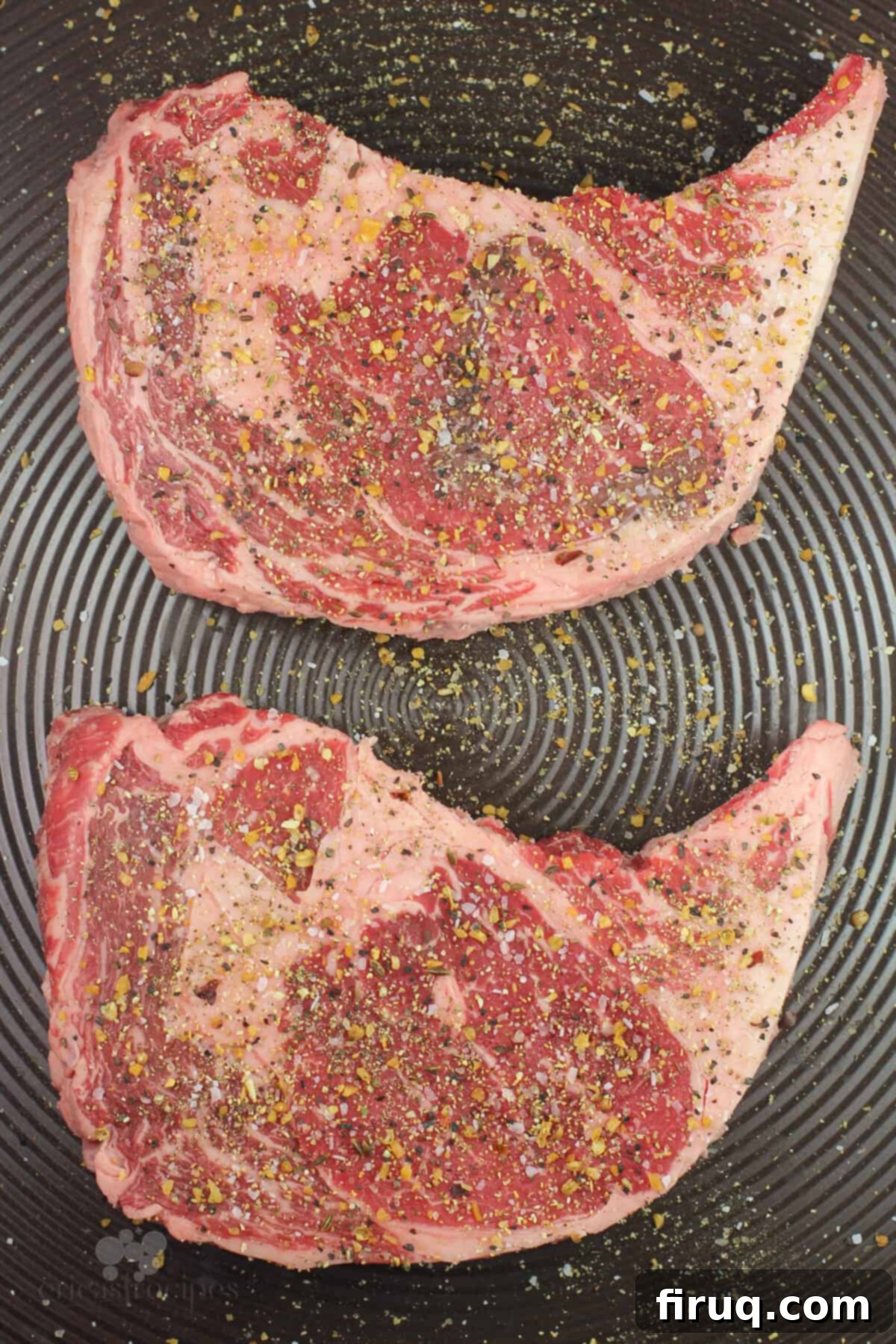 Grilled Steak with Zesty Horseradish Dijon 5 Four seasoned raw steaks ready for grilling, arranged on a metal sheet tray.