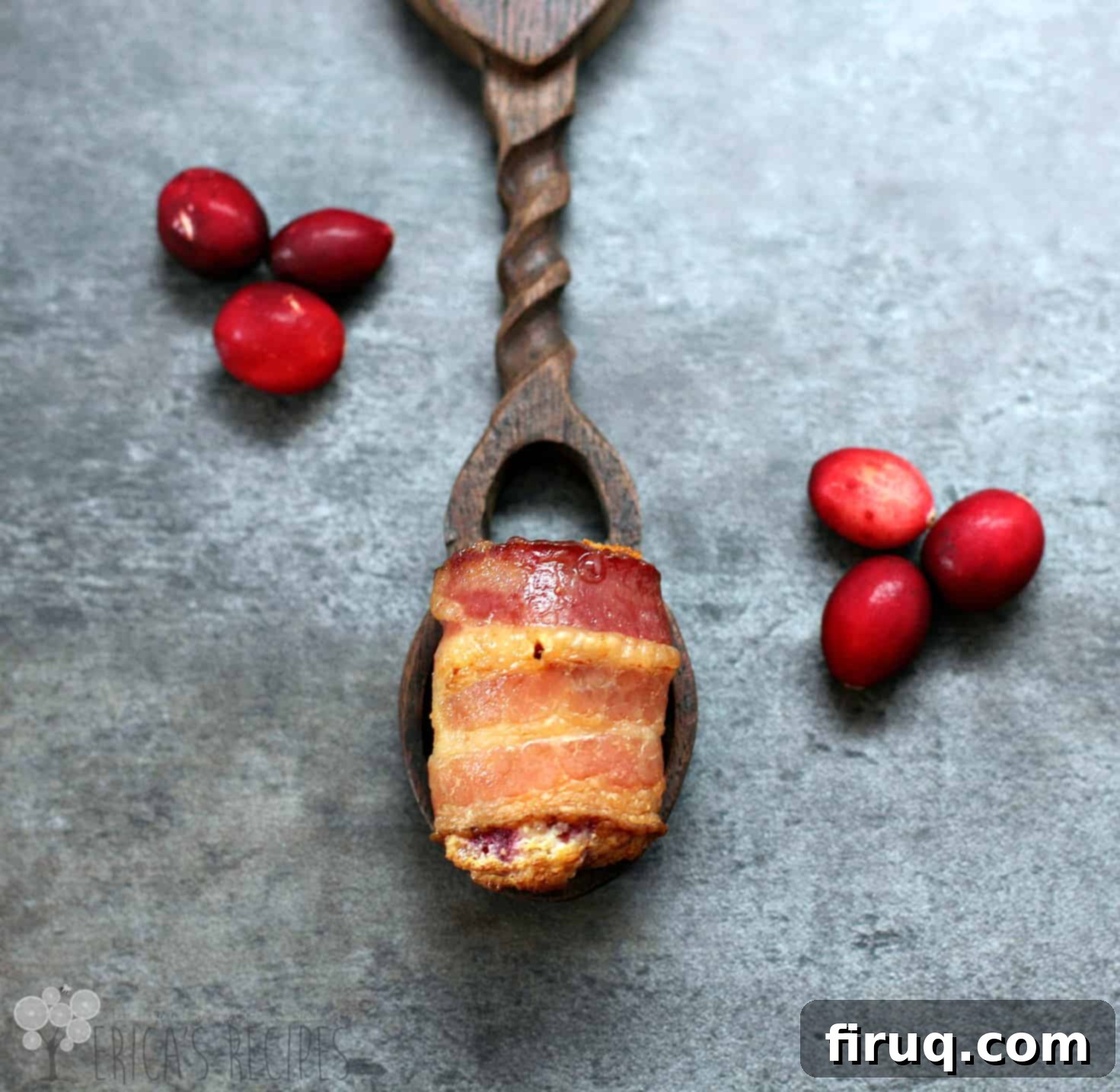 Sweet and Savory Cranberry Cream Bacon Bites 2 bacon wrapped bite on wood spoon, cranberries sprinkled around; blue background
