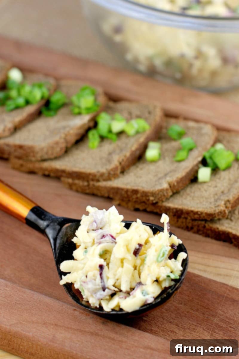 Imperial Russian Garlic Cheese 6 A beautifully arranged Russian black and orange spoon holding a portion of the creamy Russian Garlic Cheese Spread, ready to be served on a platter of party bread in the background.
