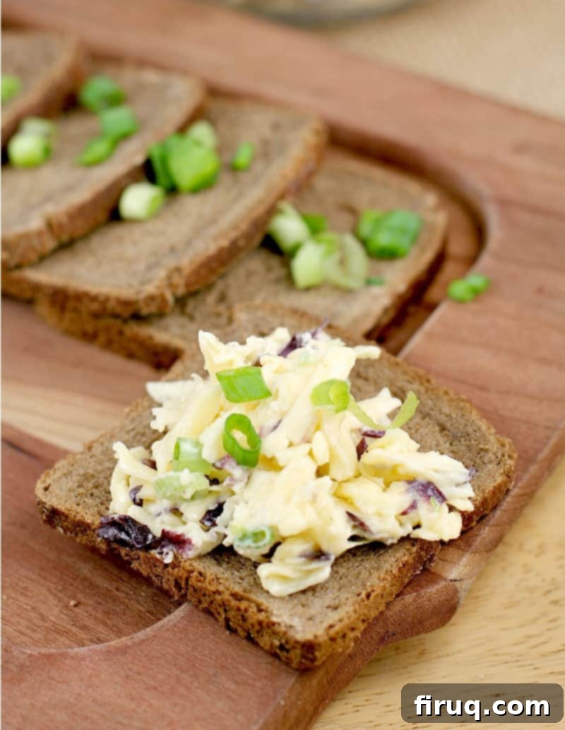 Imperial Russian Garlic Cheese 7 Square pieces of pumpernickel party bread arranged on a cutting board, with one piece topped generously with the creamy Russian Garlic Cheese Spread, ready for serving.