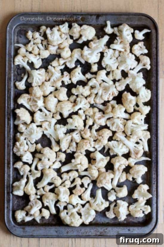 Cauliflower Florets Ready for Roasting Seasoned cauliflower florets on a baking pan.