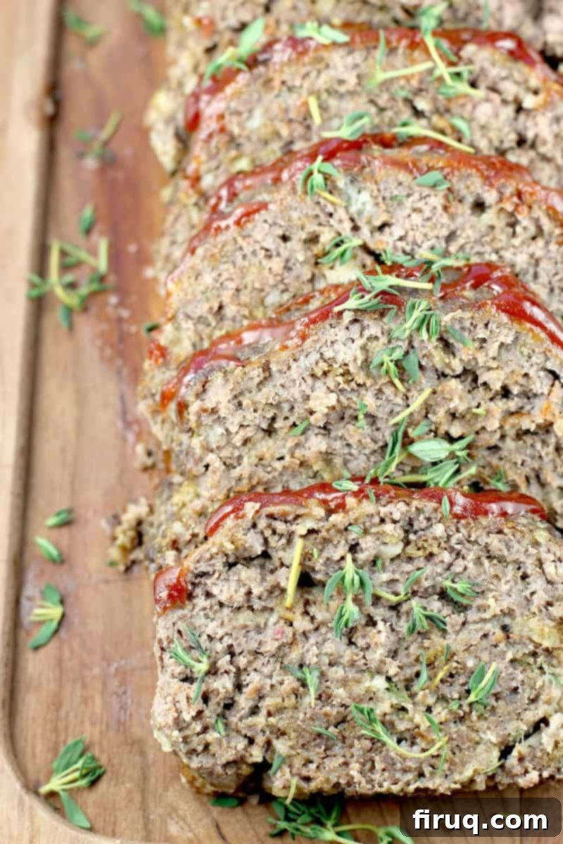 Mom's Meatloaf 2 close up of the sliced meatloaf on a wood board, thyme sprinkled over